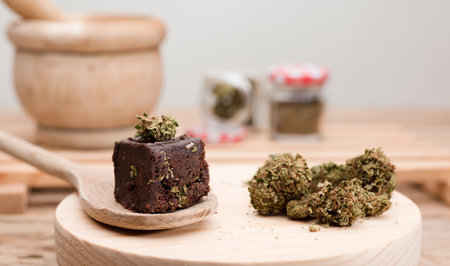 Chocolate cupcake muffins with cannabis buds. Marijuana hemp medical drugs in food dessert. Chocolate herb muffins cooking. Marijuana cake on a brown wooden table.の写真素材