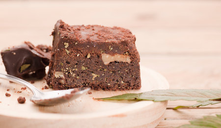 Chocolate cupcake muffins with cannabis buds. Marijuana hemp in food dessert. Chocolate herb muffins cooking. Marijuana cake on a brown wooden table.の写真素材