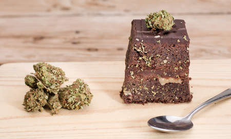cannabis buds and chocolate cupcake muffins with cannabis buds. Marijuana hemp in food dessert. Chocolate herb muffins cooking. Marijuana cake on a brown wooden table.の写真素材