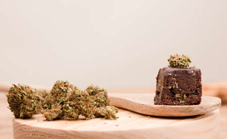cannabis buds and chocolate cupcake muffins with cannabis buds. Marijuana hemp in food dessert. Chocolate herb muffins cooking. Marijuana cake on a brown wooden table.の写真素材