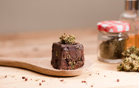 Chocolate cupcake muffins with cannabis buds. Marijuana hemp medical drugs in food dessert. Chocolate herb muffins cooking. Marijuana cake on a brown wooden table.の写真素材