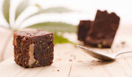 Chocolate cupcake muffins with cannabis buds. Marijuana hemp in food dessert. Chocolate herb muffins cooking. Marijuana cake on a brown wooden table. green marijuana leaf in the backgroundの写真素材