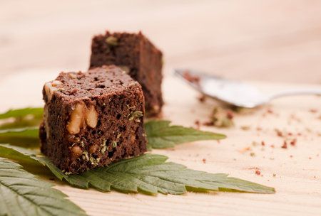 piece of brownie with marijuana, on wooden board with spoon and green cannabis leafの写真素材