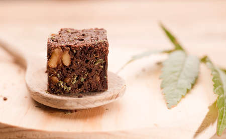 piece of brownie with marijuana, on wooden spoon and green cannabis leafの写真素材