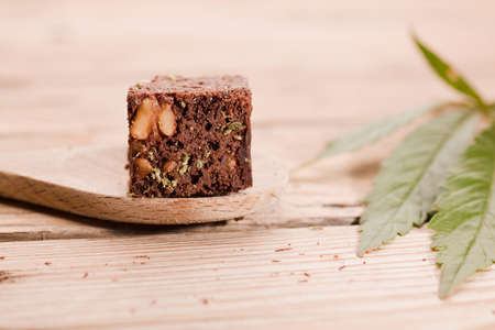 piece of brownie with marijuana, on wooden spoon and green cannabis leafの写真素材