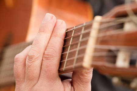 Guitar Player Hand or Musician's Hand in F Major Chord on Acoustic Guitar String in Soft Natural Light in Side Viewの写真素材