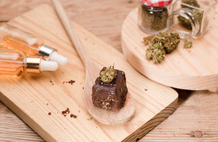 Marijuana brownie, cans of oil and jars with buds on wooden table.の写真素材