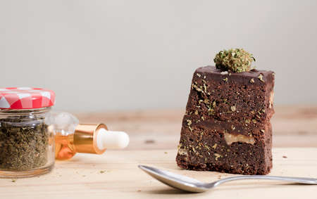 Marijuana brownie, kitchen with cans of oil and jars with buds, wooden table.の写真素材