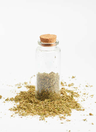 glass bottle with marijuana inside and cork stopper on crushed grass, white backgroundの写真素材