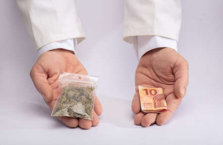 Two hands with cannabis and money. The concept of selling marijuana, hemp and drugs