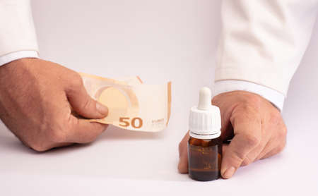 Two hands with oil cannabis and money. The concept of selling marijuana, hemp and drugsの写真素材