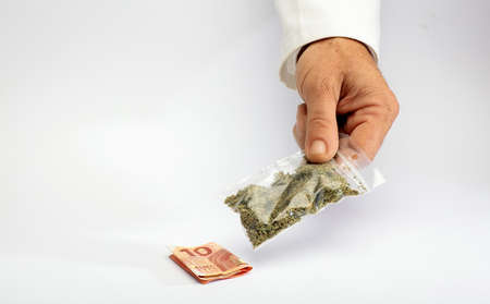 Hemp and drugs bag of marijuana in hand, delivery gestare, money, white background.The concept of selling marijuana, hemp and drugsの写真素材