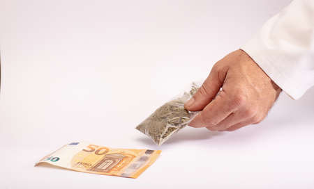 Hemp and drugs bag of marijuana in hand, delivery gestare, money, white background.The concept of selling marijuana, hemp and drugsの写真素材