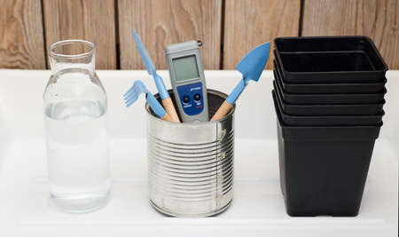 home planting kit, ph meter, water bottle, pots for plants, cultivation tools, with white and wooden backgroundの写真素材
