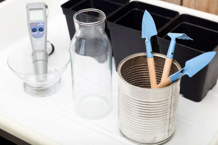 home planting kit, ph meter, water bottle, pots for plants, cultivation tools, with white and wooden backgroundの写真素材
