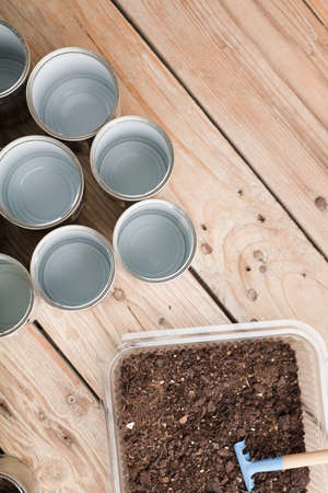 creative recycling at home, aluminum cans and recycled plastic container with soil on garden wooden tableの写真素材