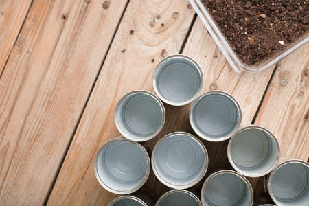 creative recycling at home, aluminum cans and recycled plastic container with soil on garden wooden tableの写真素材