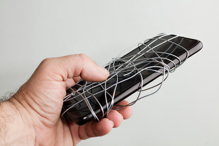 mobile coiled metal wire in the hands of a man, gray-green background, censorship of social networks. cancel cultural ban, eraseの写真素材