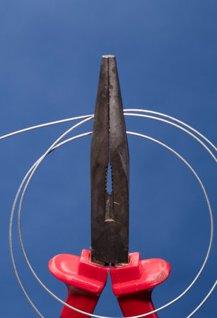 Cutting pliers with coil of wire, blue background