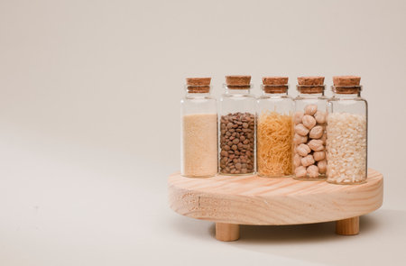 storage jar with cork stopper and lentils, breadcrumbs, rice. and chickpeas, soft green backgroundの写真素材