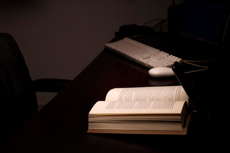 cell phone and power bank on the desk illuminates reading and study book with battery-powered computer in the background, energy poverty concept power outagesの写真素材