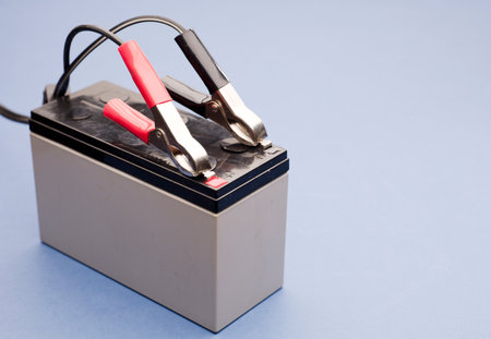 connected bolts charging battery positive pole and negative pole, blue backgroundの写真素材