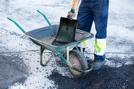 asphalt in wheelbarrow operator prepares mixture with uniformの写真素材