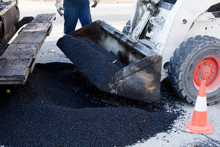bulldozer machine with asphalt on the shovel and soil background