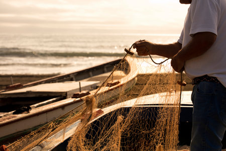 fishing net in the hands of a fisherman, preparing gear to go out to sea, in the background the Mediterranean coastの写真素材