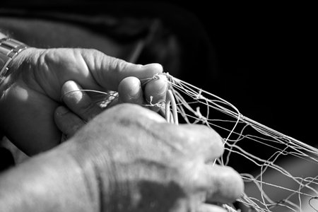 fishing net in the hands of a fisherman, with a needle and thread, black and white photography