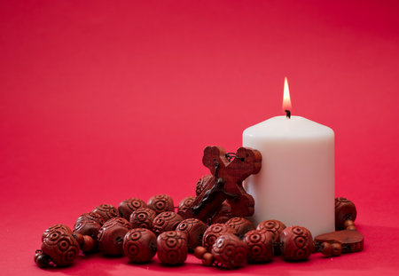 red wooden catholic rosary with lit white candle, on red background, space for textの写真素材