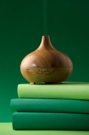 wood fragrance on the table, with natural oils essence vapor, man hands with books various greenish tones and green backgroundの写真素材