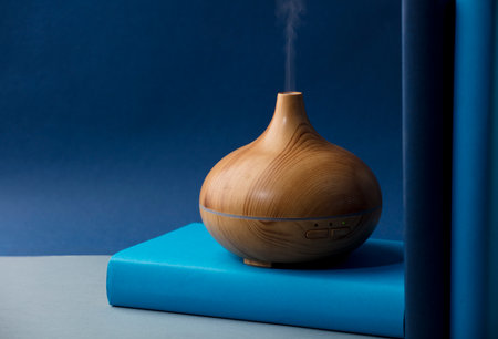 wood fragrance on the desk table with natural oils essence vapor, with blue and teal colored booksの写真素材