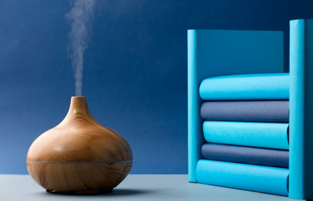 wood fragrance on the table with natural oils essence vapor, with blue and teal colored booksの写真素材