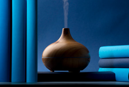 wood fragrance on the desk table with natural oils essence vapor, with blue and teal colored books