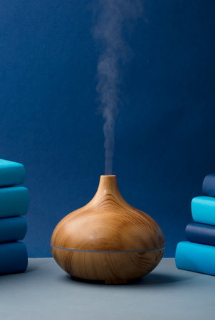 wood fragrance on the table with natural oils essence vapor, with blue and teal colored booksの写真素材