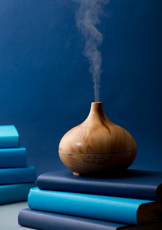 wood fragrance on the desk table with natural oils essence vapor, with blue and teal colored books