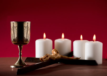 golden chalice with crucifix and burning candles red backgroundの写真素材