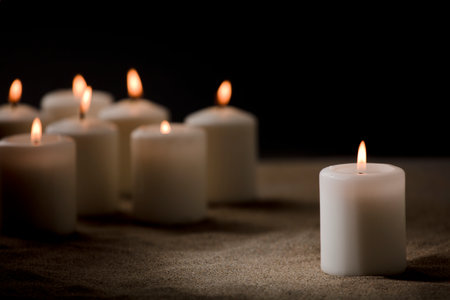 set of burning candles on sand with a black backgroundの写真素材