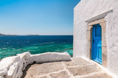 Mykonos, Greece. Traditional white building with blue door at the seaside.の写真素材