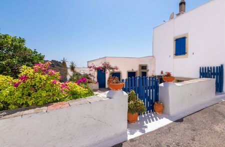 Chora town with white Greek house, blue gate and decorative pottery along the street, Kythira Island, Greece.の写真素材