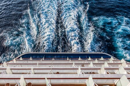 Aerial view of balcony staterooms on the aft of a sailing cruise ship.