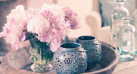 Still life with pastel peony flower bouquet in vase and lanterns on rustic wooden plate. Interior and home decoration. Soft pastel colors.の写真素材