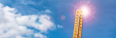 Thermometer against blue sunny sky. Hot summer weather concept.の写真素材