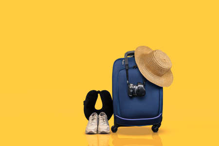 Blue hand luggage and essential travel items against yellow background.の写真素材
