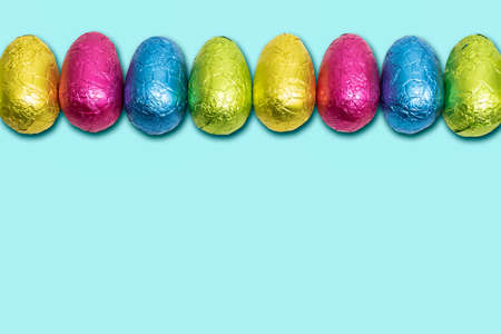 Chocolate Easter eggs wrapped in foil. Colorful Easter egg border.の写真素材