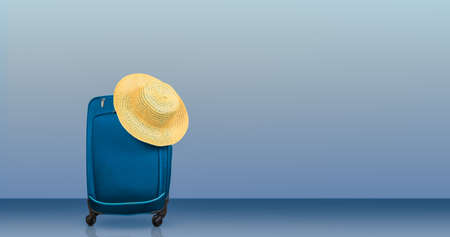 Travel suitcase and summer hat against blue background. Travel and vacation concept.の写真素材