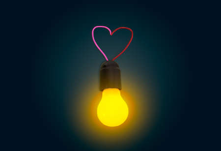 Glowing light bulb in lamp socket with electrical wires in the shape of a heart in the dark.の写真素材