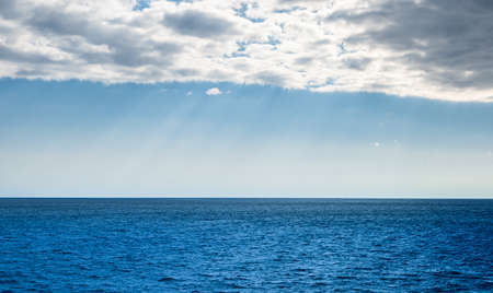 Cloud cover over blue clear sky with sunbeams over the Mediterranean sea. Weather and climate...