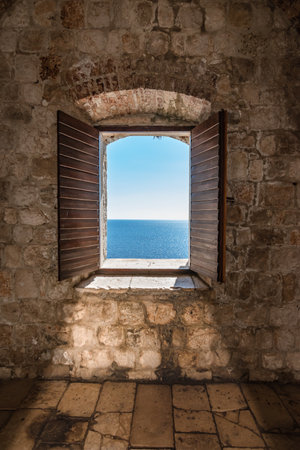 Sunlight shines through the open window overlooking the sea.の写真素材